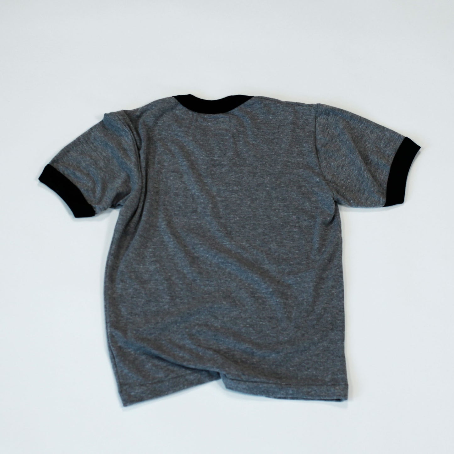 The back of our Flowerboy short sleeve baseball Tee with our digital or pixelated Flowerboy Logo with a red heart printed on the chest. The tee is grey with a black collar and black arm sleeves and back has no print. 