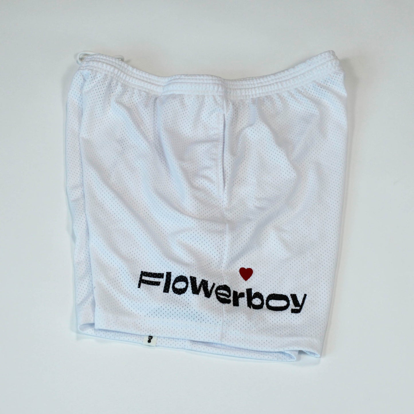 Side view of our Flowerboy black basketball shorts with printed Flowerboy Logo with red heart and a Flowerboy Tag.